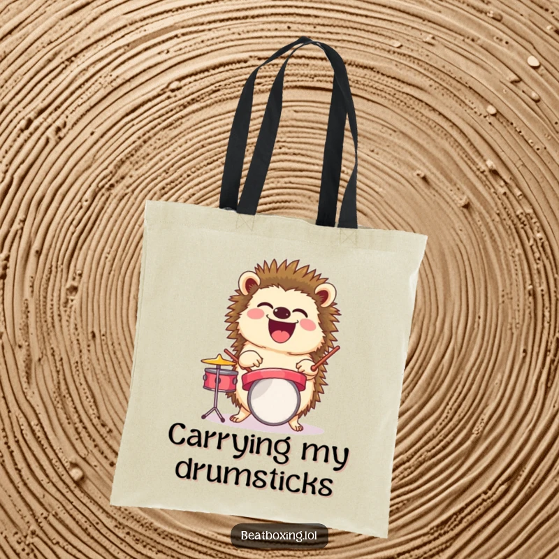 Funny tote bag with a laughing hedgehog balancing a tiny drum set, a humorous and practical gift.